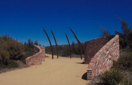 ACT Bushfire Memorial showing the pathway to the sculpture. The memorial brick walls are on either side of the path.