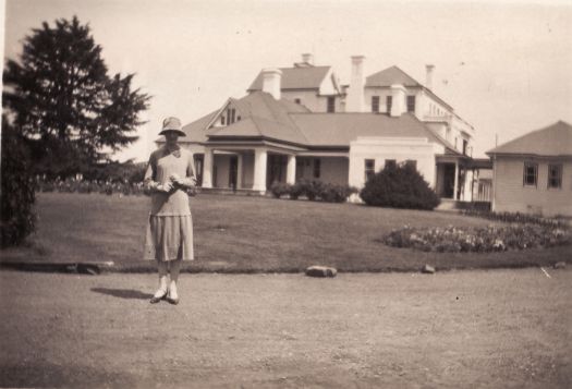 A front view of Government House, Yarralumla with an unidentified lady standing on the road