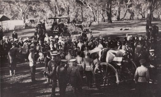 Funeral of General Bridges who died from wounds received on Gallipoli 18 May 1915. Buried at Mt. Pleasant overlooking RMC Duntroon on 3 September 1915. Photograph shows the flag-draped casket mounted on a  gun carriage at the gravesite. A charger (with boots reversed in stirrups) is shown behind the carriage. Large number of dignitiaries present.