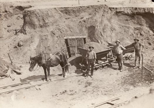 Building Cotter Dam shows three men loading two skips pulled by one horse on a tram line