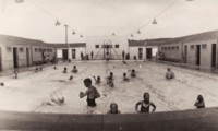 Shows the Manuka Swimming Pool with people in the water
