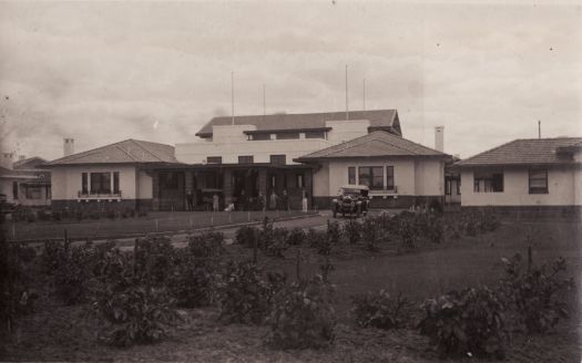 Hotel Canberra front entrance with nine unidentified people and cars in front