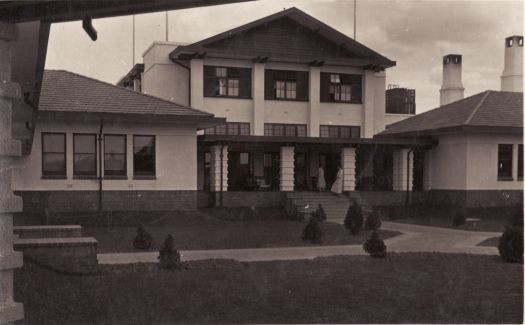 Rear view of the Hotel Canberra with two women on the steps  