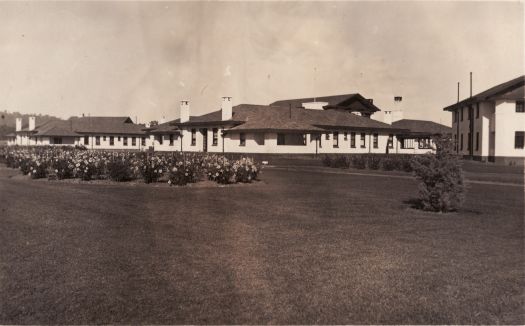 A side view of the Hotel Canberra from the north east showing the lawn and flowers