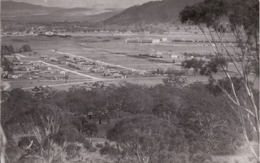 View towards city from Mt Ainslie (about the War Memorial) showing glimpse of the Ainslie tradesmen camp in trees at foreground centre.