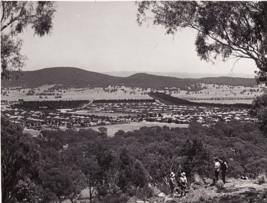 View over Braddon from Mt Ainslie towards Haig Park and Black Mountain. Four people in the foreground.