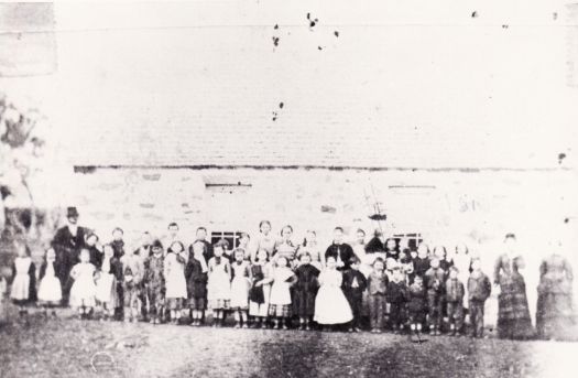 St. John's Schoolhouse with students and teachers outside.