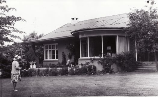 A woman standing in the garden looking at the front view of Booroomba Homestead