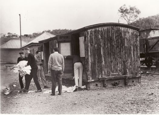 Clearing papers from a shed at Captains Flat. Railway trucks are in the background.