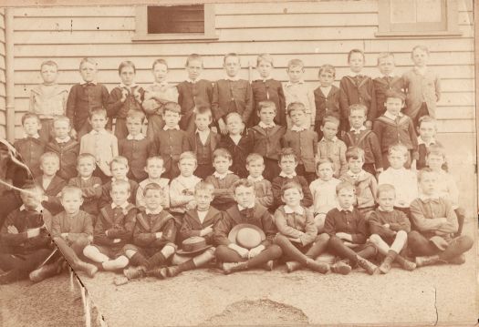 School photo showing four rows of 47 boys aged under 10 years in front of a weatherboard building circa late 1800s to early 1900s.