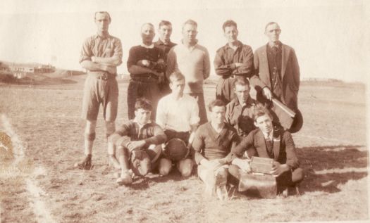 Shows six men standing and five sitting or kneeling, one of whom is holding a soccer ball. On the bottom is written '1923'.