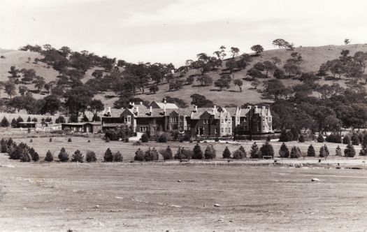 View of the Church of England Grammar School in Red Hill from across a paddock with Red Hill in the background.