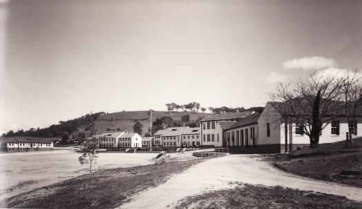 Photograph shows living quarters and most of the parade ground with the administration building in the background.