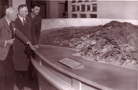 Three men looking at model of Gallipoli landscape.
