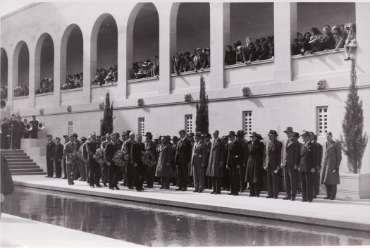 A ceremony (probably on Anzac Day) near the Pool of Remembrance at the Australian War Memorial. In the foreground of the photograph are men carrying wreaths.