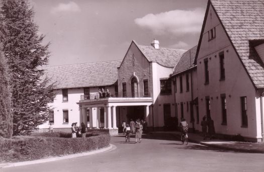 Hotel Ainslie front entrance from Limestone Avenue with women entering, leaving, standing and one riding a bicycle.