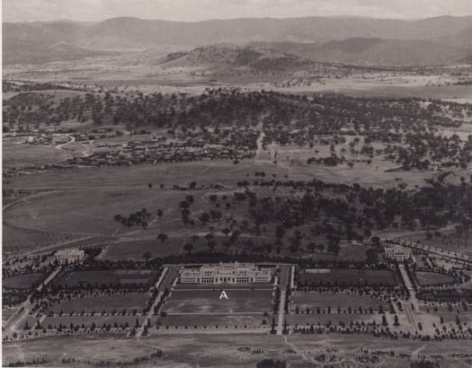 Aerial view to south over Parliament House to Red Hill and Mt Taylor showing East and West Blocks and King George V statue site marked 