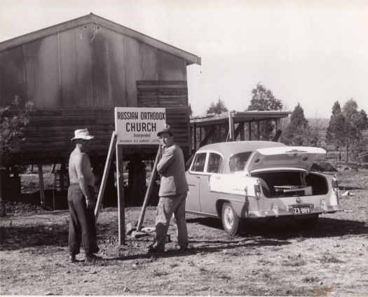 Two men in front of sign for Russian Orthodox Church, Kingston