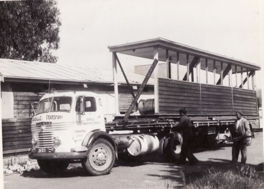 Russian Orthodox Church site with Sebille Transport Service truck carrying half a building, and two men