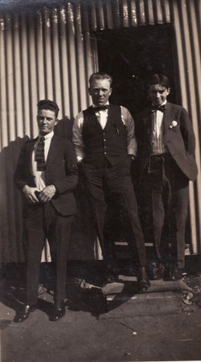 Three well-dressed young men in front of living quarters at the Causeway, after a fire.