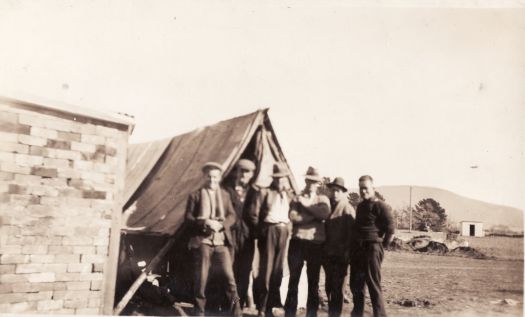 My shack and myself. Six men in front of a tent.