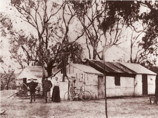 Arneson residence at the Department of Home Affairs camp, Duntroon. Left to right - Dick Arneson, Anton Arneson, Kathleen Arneson and Arthur Arneson (standing near a bicycle).