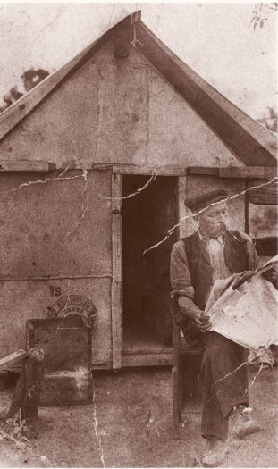 Anton Edward Arneson, sitting outside a 6'x 8' tent at Duntroon, reading a newspaper and smoking a pipe