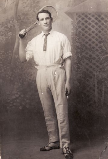 William Byrne Freebody with tennis racquet. On the back is written \"courtesy of Chas Hawes\".