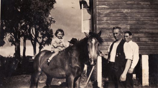 Two men with child on pony