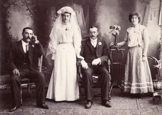 Wedding portrait of unnamed couple with bridesmaid and best man.