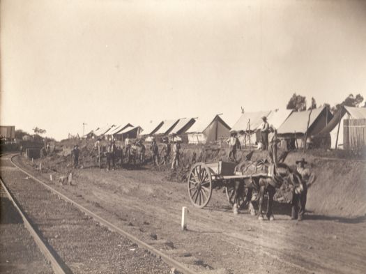Tent camp and workmen by railway line
