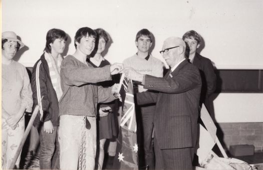 Cam Morris (CDHS) with six Marist College students, presenting an Australian flag