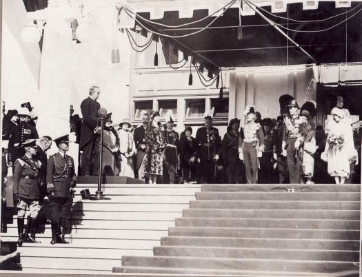 The Right Honourable S.M. Bruce, Prime Minister, addressing the Duke and Duchess of York on the steps of Parliament House. Dame Nellie Melba by microphone.
