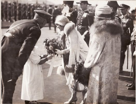 The Duchess of York receives a bouquet of flowers from a small girl at the ceremony to open Parliament House. The Duchess became Queen Elizabeth when her husband ascended to the throne as King George VI.