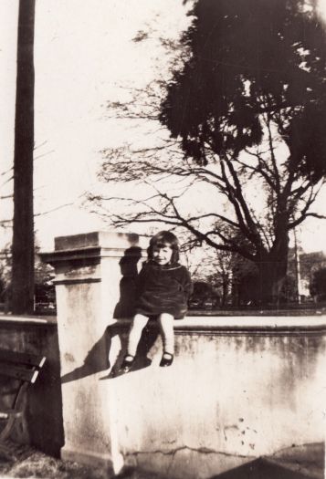 Unnamed little girl sitting on a concrete wall