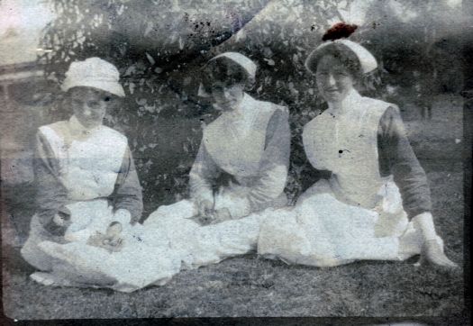 Three nurses sitting on the ground, one is \"Susan\"