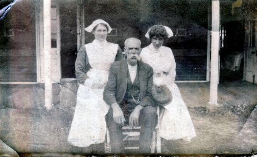 An old man flanked by two nurses