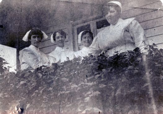 Four nurses standing outside verandah.