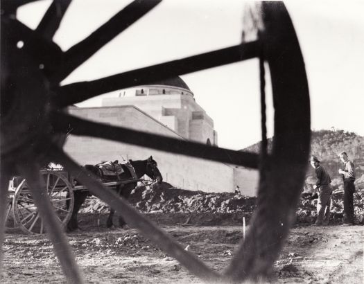 Construction workers preparing grounds of Australian War Memorial circa 1940. Photo taken through the spokes of a horse drawn cart.