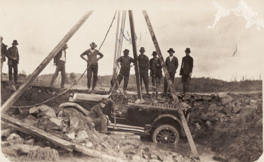 Nine workmen with car being lifted by a crane out of the creek which now runs under Telopea Park (Black Spring Creek).