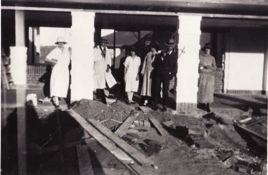 Group standing in front of partly built Hotel Canberra. 

Left to Right : unknown woman, Reg Burton, Nellie Masters (Mrs Bill Scott), Mrs Imelda Falconer, Ray Walter Hyles \"Woodlands\", Frances Falconer (Mrs R.W. Hyles).