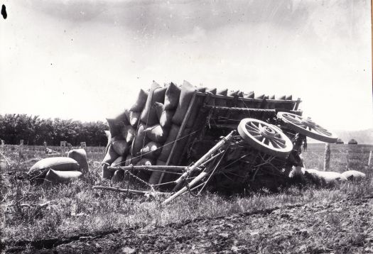 Cart overturned on Springbank farm. It is loaded with bags of grain.