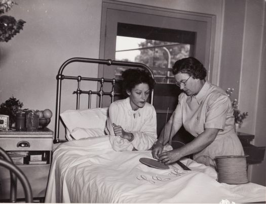 Occupational therapy, Canberra Community Hospital. Nurse showing a female patient in bed how to make a basket.