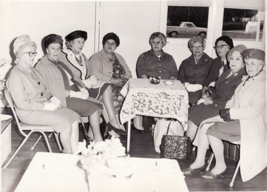 Nine members of the Canberra Country Women's Group sitting around a table