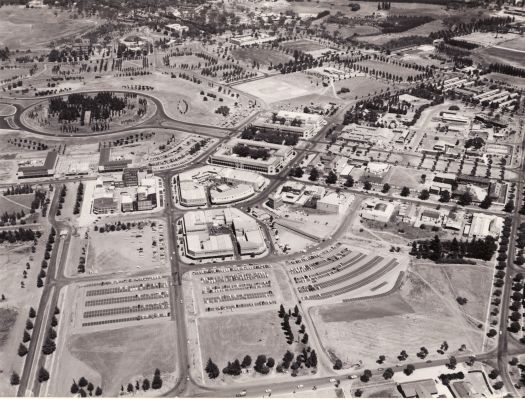 Canberra and Civic area from the air, taken over Petrie Street looking west. Ainslie Avenue is at left, Ballumbir Street with cars at the botttom. Bunda Street runs from Mort Street to Ainslie Avenue and their are cars in the adjacent car park. Shows the completed Perth, Brisbane and Newcastle Buildings and the North and South Buildings in Civic Square.