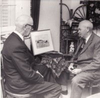 Presentation of a watercolour painting of Blundell's Cottage, by H.M. Rolland, to A.C. Morris, President of the Canberra & District Historical Society. Photo shows two men sitting on chairs admiring the painting.