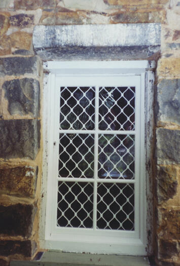 A close up of a window covered by a screen at Blundell's Cottage.