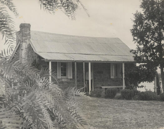 Front view of Blundell's Cottage showing a man and a child standing in the doorway.