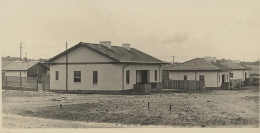 View of houses in Forrest looking along an unidentified street. There are no lawns, only dirt at the front of the houses.