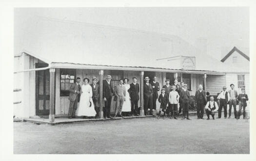 Cricketer's Arms Hotel, Hall, was a long building with a verandah. The photograph shows a group of people on the verandah. The Cricketers Arms was the last licensed hotel in the Territory when it closed in 1918. The last licensee was Morris Lazarus.